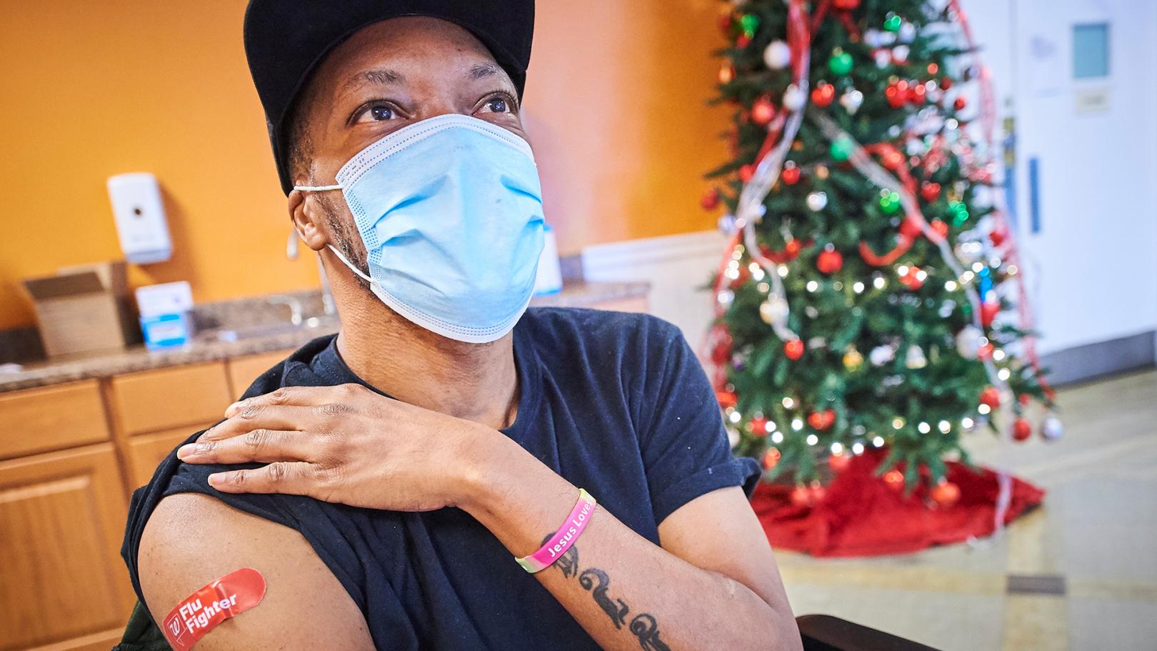 men wearing a face mask showing the plaster on his arm after